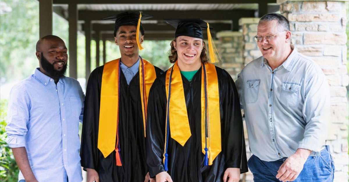 Two graduate students wearing a yellow graduation stole